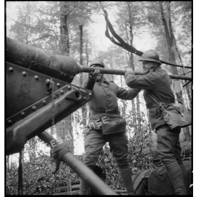 Des servants d'un  220 mm long M1917 donnent un coup de refouloir pour mettre une munition à poste.