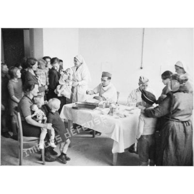 Dans un hôpital, consultation pour enfants réfugiés par un médecin militaire de la 5e armée et une infirmière.