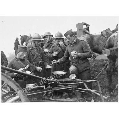 Après le travail aux champs des soldats de la 5e armée mangent près d'une machine agricole.