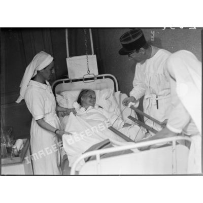 Dans un hôpital, une infirmière et un médecin donnent des soins à une femme âgée du secteur de la 5e armée.