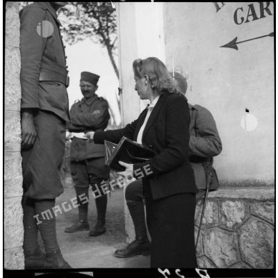 Une femme discute à l'entrée du stade d'Antibes avec des tirailleurs de la 6e armée.