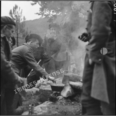 Des chasseurs du 9e BCA sont regroupés autour d'un feu de camp pour faire chauffer un café.
