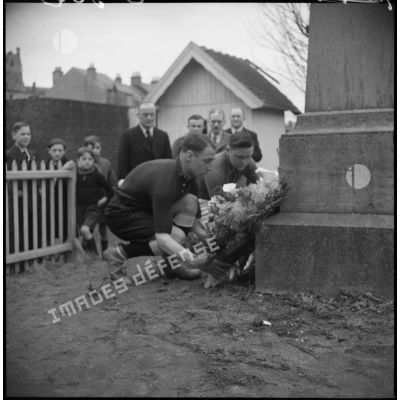 Deux rugbymen français et britannique déposent une gerbe de fleur au pied d'un monument aux morts.