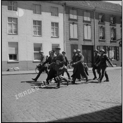 Des soldats et un officier belge dans une rue.