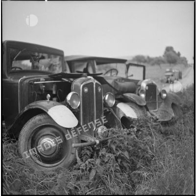 Deux épaves de voitures civiles laissées à l'abandon dans un champs.