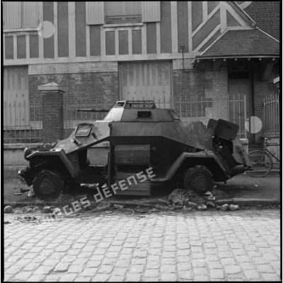 Un blindé allemand en ruine abandonné dans une rue.