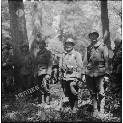 Des soldats de la 7e armée sont alignés au garde-à-vous dans une forêt.