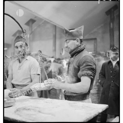 Des soldats pèsent la farine à l'aide d'une balance.