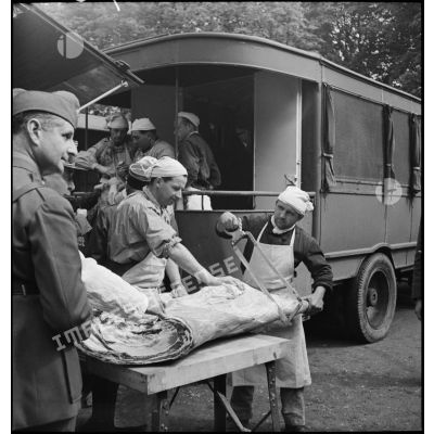 Soldats découpant une importante pièce de viande.
