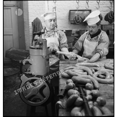 Bouchers préparant des saucisses dans un atelier de boucherie.