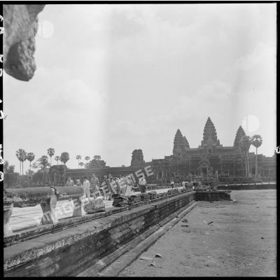 Le général Clark et son épouse accompagnés d'un délégation avancent sur une grande allée d'Angkor Vat.