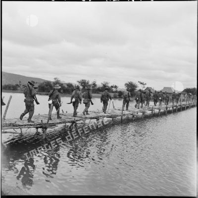 Progression de la 3e compagnie du 73e BG (bataillon du génie) sur un pont de bambous à l'entrée d'un village, au cours de l'opération Atlante.