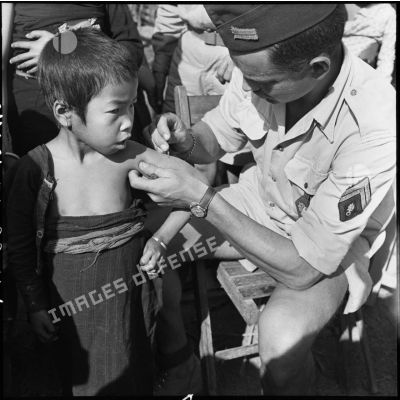 Vaccination d'un enfant Thaï par un sergent légionnaire dans un village de la vallée de Diên Biên Phu.