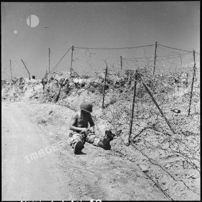 Un monteur de ligne réparant les dégâts causés par l'artillerie Viêt-minh, près du centre de résistance Isabelle du camp retranché de Diên Bien Phu.
