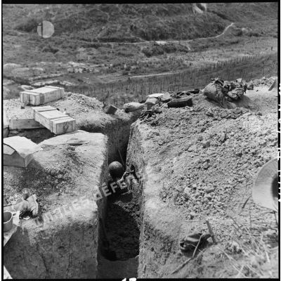 Soldat creusant à Diên Biên Phu une cavité dans la paroi d'une tranchée à des fins de rangement.