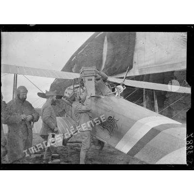 Saint-Amand, Aisne, camp d'aviation. La mise en place d'un appareil photographique sur un avion. Novembre 1917. [légende d'origine]