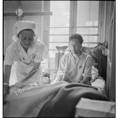 Dans le pavillon des "troupes indigènes", une infirmière donne des soins à un blessé.