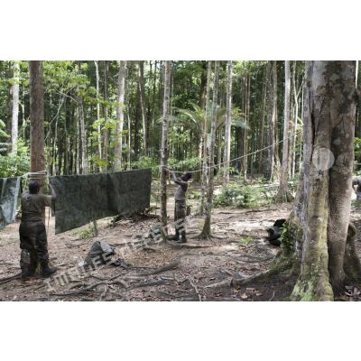 Des stagiaires du régiment du service militaire adapté (RSMA) tendent une bâche pour le montage d'un bivouac lors d'un atelier jungle à Saint-Jean-du-Maroni, en Guyane française.