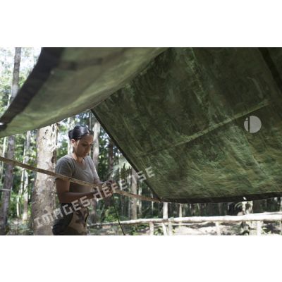 Une stagiaire du régiment du service militaire adapté (RSMA) tend une bâche pour le montage d'un bivouac lors d'un atelier jungle à Saint-Jean-du-Maroni, en Guyane française.