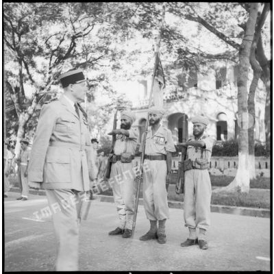 Défilé du 14 Juillet à Lang Son. Le  colonel Constans, commandant le secteur de Lang Son, passe en revue le fanion du GTMEO (Groupement des tabors marocains en Extrême-Orient).