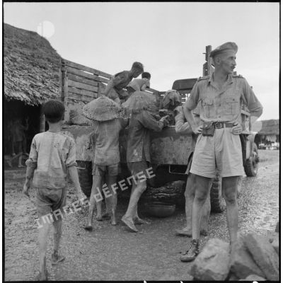 Déchargement de briques d'un camion par des villageois pour la construction de digues contre l'inondation, sous la surveillance de militaires du 1er régiment de chasseurs (RCh).