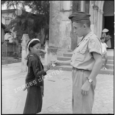 Un militaire donne un billet à une enfant vietnamienne à la sortie de la messe en la cathédrale d'Hanoï.