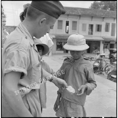 Un militaire donne un billet à un enfant vietnamien à la sortie de la messe en la cathédrale d'Hanoï.