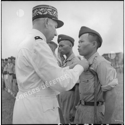 Remise de décoration à un lieutenant du BMI (bataillon de marche indochinois) par le général Marchand au cours d'une cérémonie sur le stade d'Haïduong.