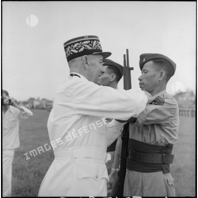 Remise de décoration à un caporal du bataillon de marche indochinois (BMI) par le général Marchand au cours d'une cérémonie sur le stade d'Haïduong.