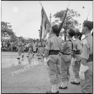 Le BMI (bataillon de marche indochinois) défilant devant le drapeau du 1er RTT (régéiment de tirailleurs tonkinois) à Haïduong.
