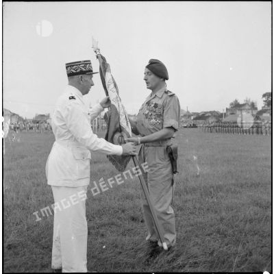 Le général Marchand, adjoint du commandant de la zone opérationnelle du Tonkin, remet le drapeau de l'ancien 1er RTT (régiment de tirailleurs tonkinois) au capitaine Bigeard, commandant le BMI, sur le stade d'Haiduong.