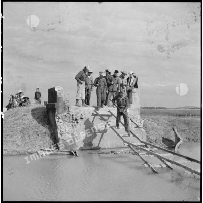 Passage d'un soldat du Génie muni d'un détecteur de mines sur des planches de bois remplaçant un pont détruit sur la route coloniale n°1 au Tonkin.