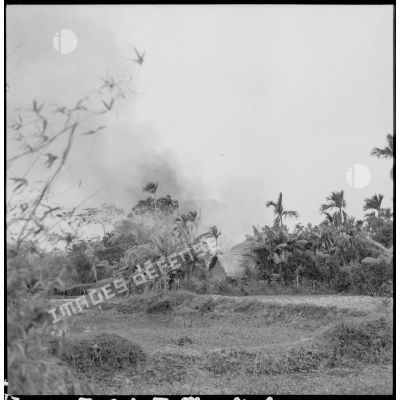 Les hommes du commando trouvent les habitations du village en feu au cours de l'opération Barbe.