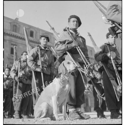 Une section d'éclaireurs skieurs du 43e régiment d'infanterie alpine (RIA) est rassemblée sur la place d'armes de la caserne du Muy avec son chien mascotte.