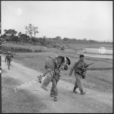 Un tirailleur transporte sur son dos un camarade blessé lors des combats de Huong Canh.
