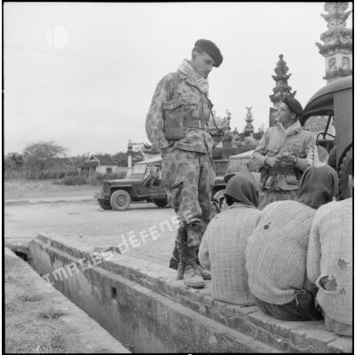 Des parachutistes stationnés devant la pagode de Huong Kanh interrogent des vietnamiens.