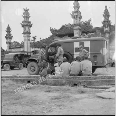Des parachutistes stationnés devant la pagode de Huong Kanh interrogent des autochtones.