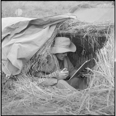 Soldat transmettant des instructions à la radio dans un abri camouflé sur la cote 210 lors des combats de Vinh Yen.