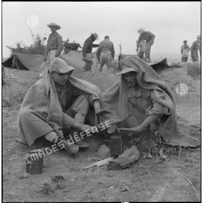 Des soldats du groupe mobile n°3 (GM3) tentent de se réchauffer tout en faisant chauffer une gamelle sur la cote 210 lors des combats de Vinh Yen.