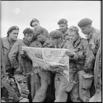 Un groupe de commandos marine lit le journal L'Equipe à bord d'un LCI (landing craft infantry) en baie d'Along.