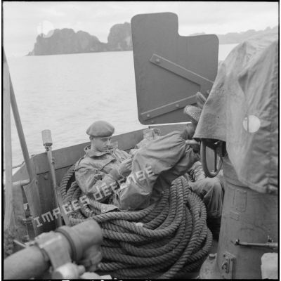 Un commando marine lit un roman au cours de la traversée de la baie d'Along à bord d'un LCI (landing craft infantry).