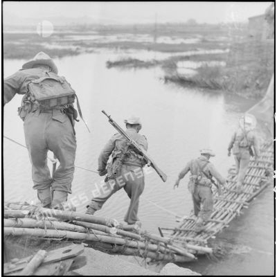 Passage d'un pont en bambou par les premiers éléments du groupement "Sizaire" armés de FM M24/29 et MAS 36.