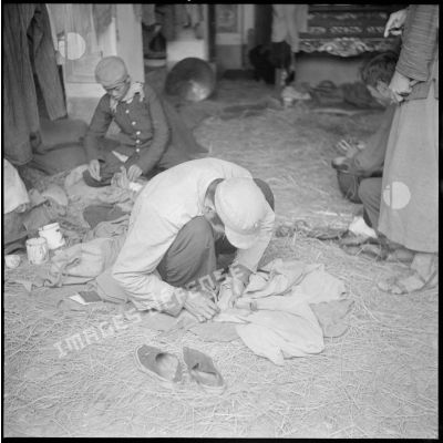Un soldat nationaliste chinois interné à Moncay raccomode ses vêtements.