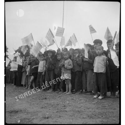 Au pont de Canh-Lanh, les enfants agitent des petits drapeaux aux couleurs vietnamiennes au cours de la visite du général Marchand.