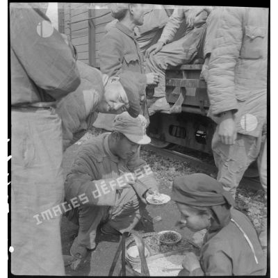 Des soldats internés de l'armée nationaliste chinoise mangent sur un quai de gare au cours d'un transfert de Hanoï vers Haïphong.