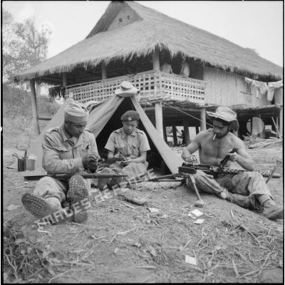 Préparation de l'armement avant de partir en opération par un goumier du 17e tabor, un partisan et un parachutiste.