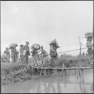Franchissement d'un arroyo sur un pont de fortune par une compagnie de parachutistes au cours de l'opération Méduse.