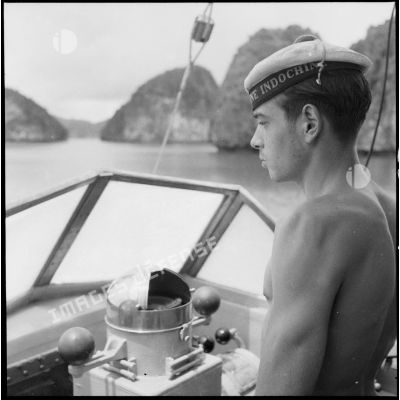 En baie d'Along, un matelot d'équipage à la barre du garde-côtes.