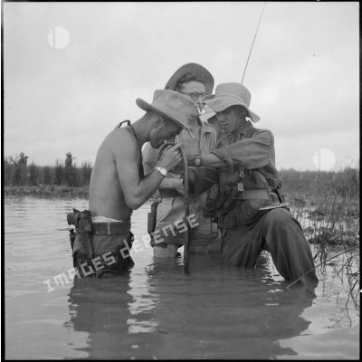 Dans l'eau jusqu'à la taille, des soldats allument une cigarette.