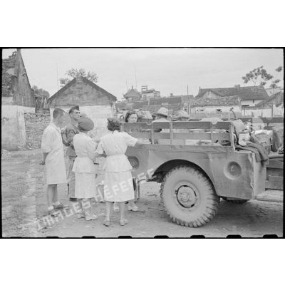 Personnel féminin et officier près d'un véhicule contenant des colis.